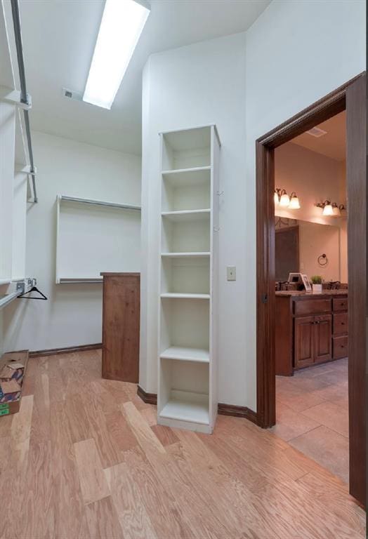 spacious closet with a skylight and light hardwood / wood-style flooring