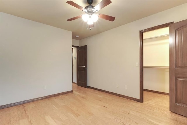 unfurnished bedroom featuring ceiling fan, light wood-type flooring, a closet, and a spacious closet