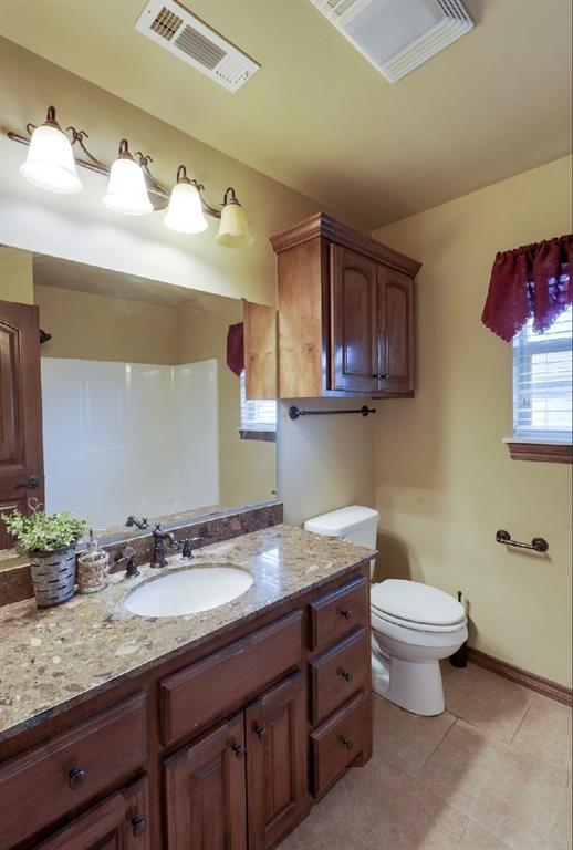 bathroom with toilet, vanity, and tile patterned flooring