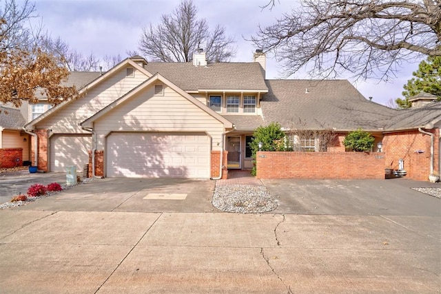 view of front of property featuring concrete driveway, an attached garage, a shingled roof, brick siding, and a chimney