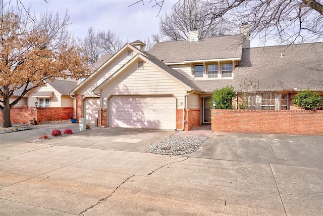 traditional-style house with fence, an attached garage, a shingled roof, concrete driveway, and brick siding