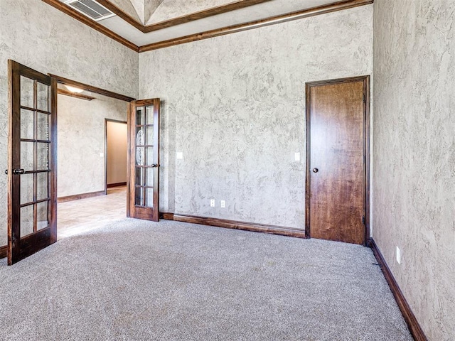 carpeted empty room featuring ornamental molding and french doors