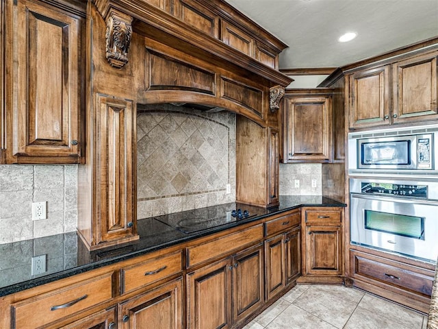 kitchen with dark stone countertops, light tile patterned floors, stainless steel appliances, and backsplash