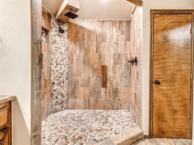 bathroom with hardwood / wood-style flooring, vanity, and a tile shower