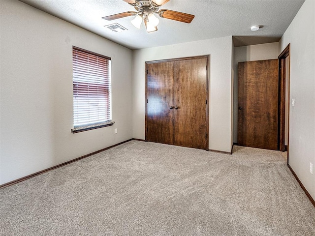 unfurnished bedroom featuring light carpet, a closet, ceiling fan, and a textured ceiling