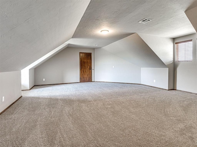 bonus room featuring light carpet, lofted ceiling, and a textured ceiling