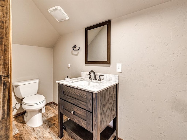 bathroom with toilet, lofted ceiling, wood-type flooring, and vanity