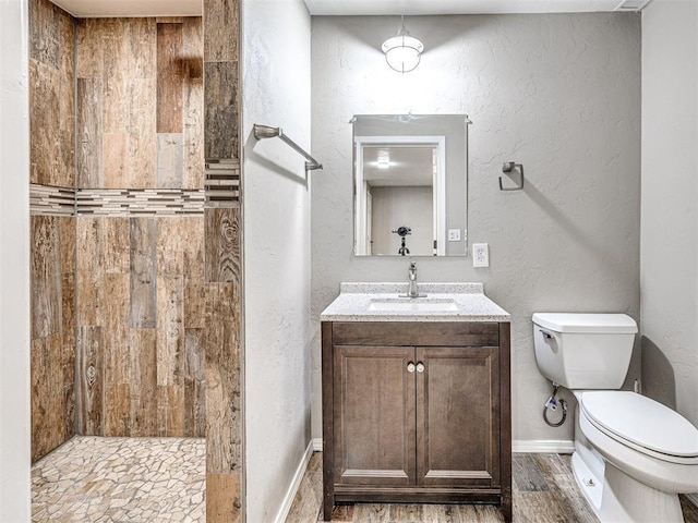 bathroom featuring hardwood / wood-style floors, toilet, a tile shower, and vanity