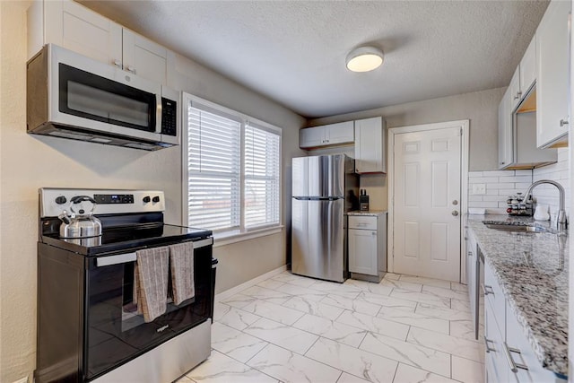 414 NW 50th St, Oklahoma City, OK 73118 - kitchen with stainless steel appliances, a sink, light marble finish flooring, light stone counters, and white cabinets