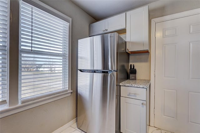 414 NW 50th St, Oklahoma City, OK 73118 - kitchen with freestanding refrigerator, light stone countertops, baseboards, and white cabinetry