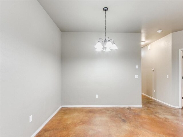 empty room featuring a notable chandelier and concrete floors