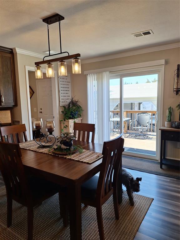 dining area featuring dark wood-style flooring, visible vents, and crown molding