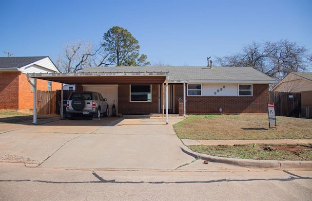 ranch-style house featuring brick siding, an attached garage, fence, a carport, and driveway