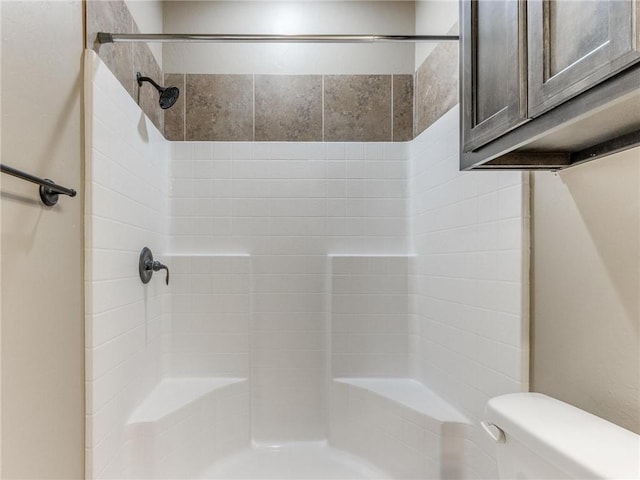 bathroom featuring a tile shower and toilet