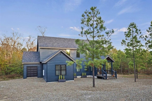 exterior space featuring an attached garage, roof with shingles, and gravel driveway