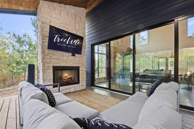 living area featuring an outdoor stone fireplace, wooden ceiling, and wood finished floors