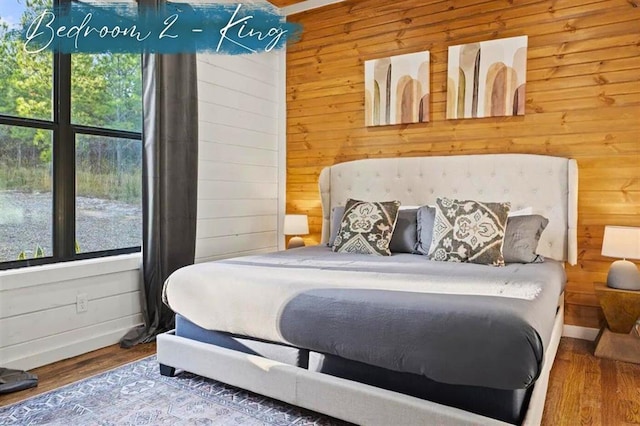 bedroom featuring wooden walls, baseboards, and wood finished floors