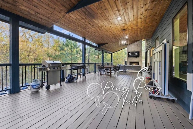 deck with an outdoor stone fireplace and area for grilling
