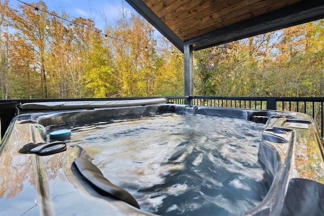 deck featuring a hot tub and a wooded view
