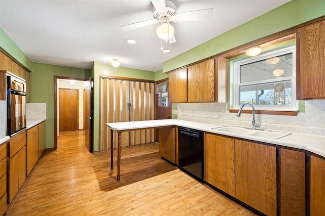 kitchen featuring tasteful backsplash, sink, light hardwood / wood-style flooring, and black appliances