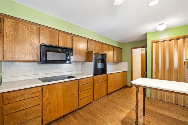 kitchen featuring tasteful backsplash, black appliances, and light wood-type flooring