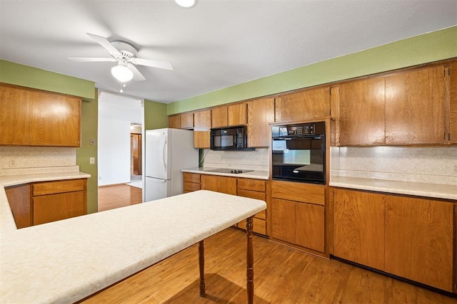 kitchen with tasteful backsplash, black appliances, light hardwood / wood-style floors, and ceiling fan