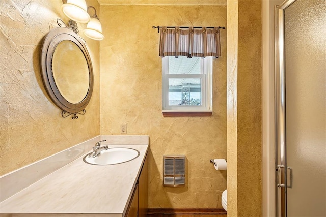 bathroom with vanity, a shower with door, and toilet