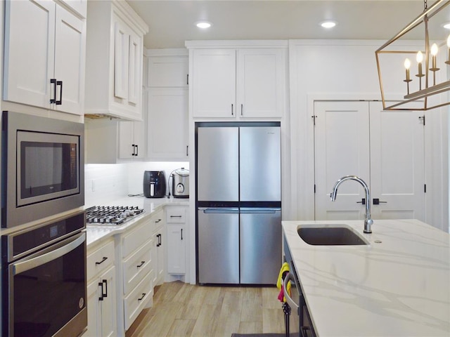 kitchen featuring stainless steel appliances, sink, pendant lighting, and white cabinets