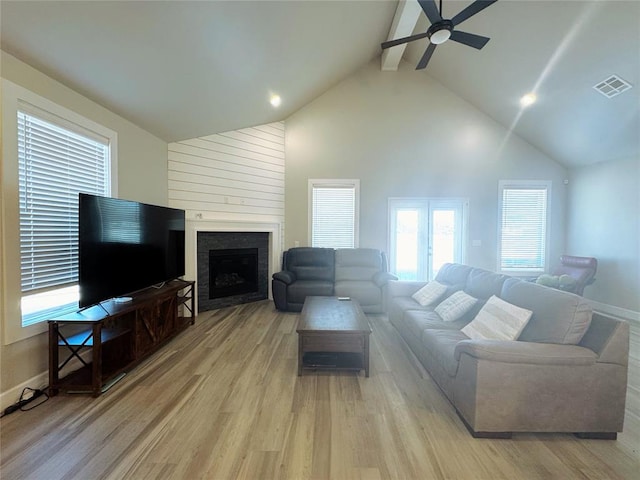 living room with high vaulted ceiling, light hardwood / wood-style flooring, a large fireplace, ceiling fan, and beam ceiling