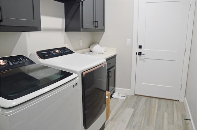 laundry area with cabinets, separate washer and dryer, and light hardwood / wood-style flooring