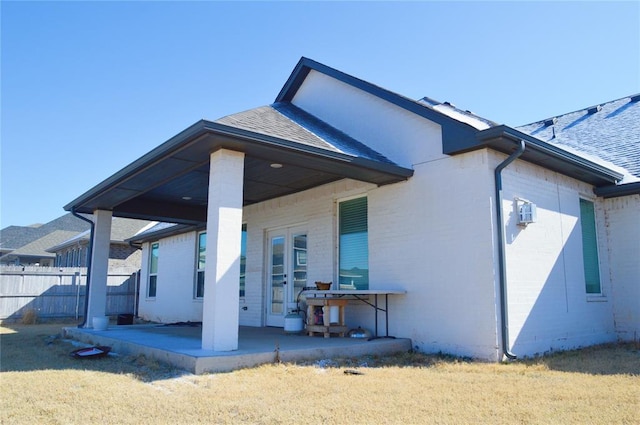 rear view of house featuring a lawn and a patio