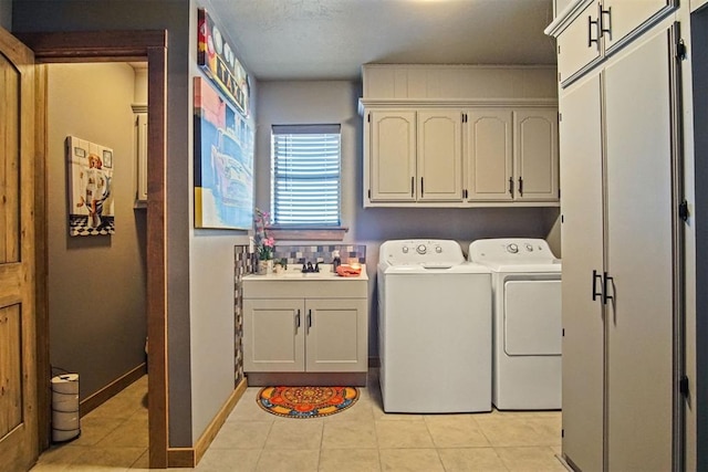 laundry room featuring cabinet space, light tile patterned floors, baseboards, washer and dryer, and a sink