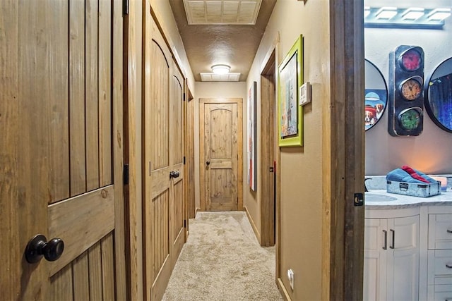 hall with light colored carpet, visible vents, and baseboards