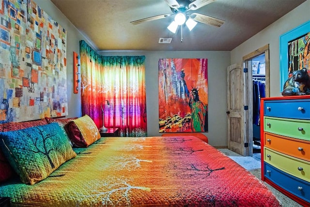 bedroom with ceiling fan, visible vents, a closet, carpet, and a walk in closet