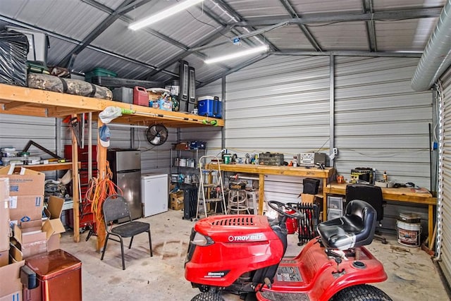 garage featuring refrigerator, metal wall, a workshop area, and freestanding refrigerator