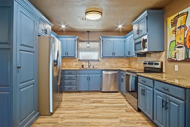 kitchen featuring appliances with stainless steel finishes, visible vents, a sink, and blue cabinetry