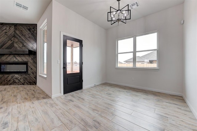 entrance foyer with light wood-type flooring, an inviting chandelier, and a healthy amount of sunlight