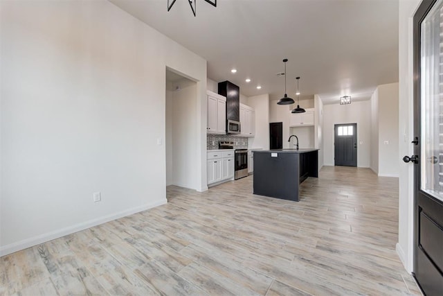 kitchen featuring a center island with sink, appliances with stainless steel finishes, pendant lighting, sink, and white cabinetry