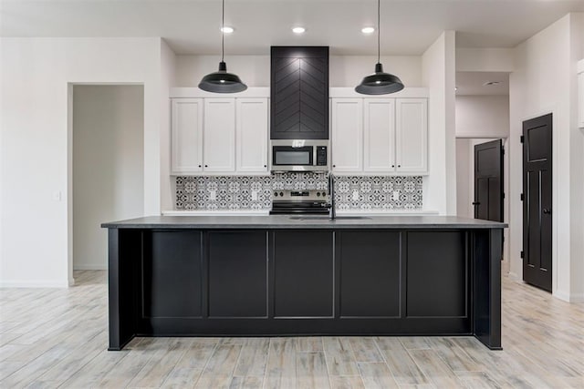 kitchen with white cabinetry, stainless steel appliances, decorative light fixtures, sink, and decorative backsplash