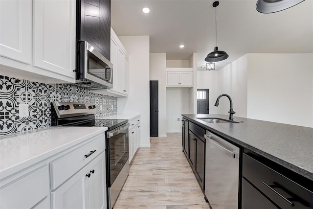 kitchen featuring white cabinetry, hanging light fixtures, stainless steel appliances, sink, and decorative backsplash