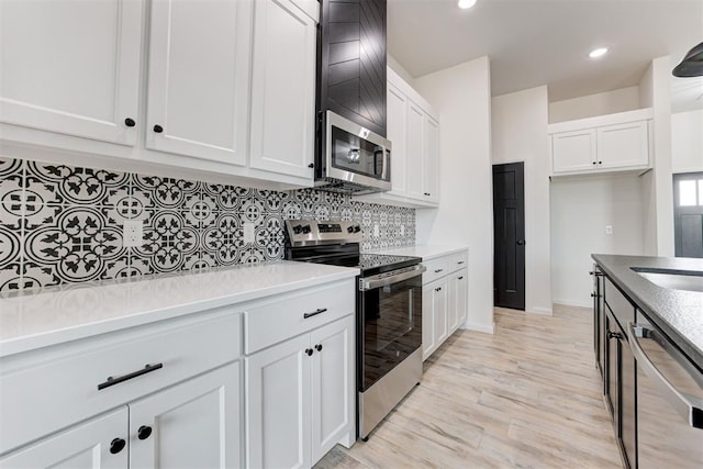 kitchen featuring appliances with stainless steel finishes, white cabinets, tasteful backsplash, and light hardwood / wood-style flooring