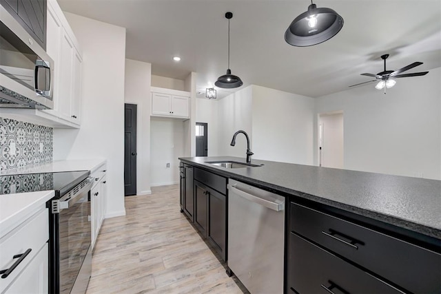 kitchen with hanging light fixtures, white cabinetry, stainless steel appliances, and sink