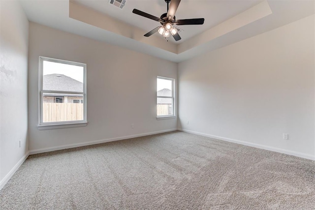 spare room featuring carpet, ceiling fan, and a raised ceiling