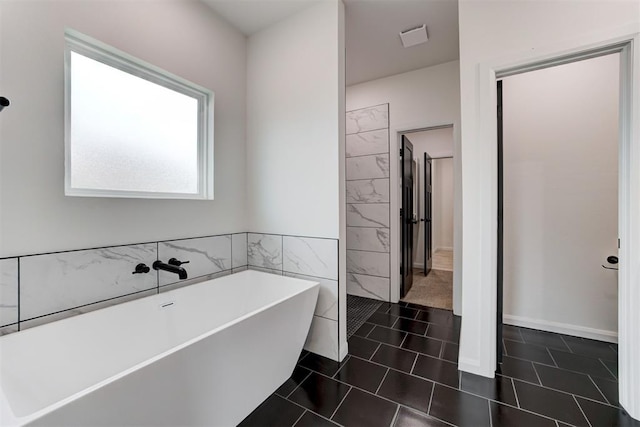 bathroom with tile patterned floors, tile walls, and a bathing tub