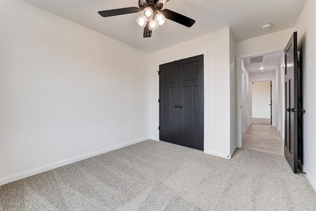 unfurnished bedroom with a closet, light colored carpet, and ceiling fan