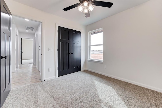 unfurnished bedroom featuring ceiling fan, light carpet, and a closet