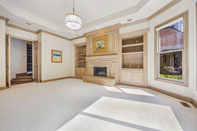 living room with built in features, light colored carpet, a stone fireplace, and a raised ceiling