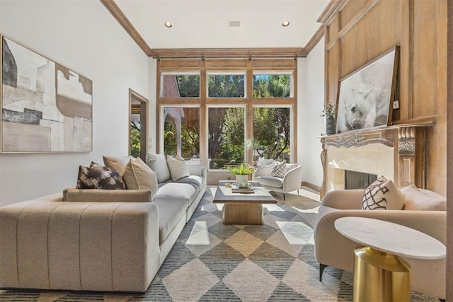 living room featuring a towering ceiling, ornamental molding, and a fireplace