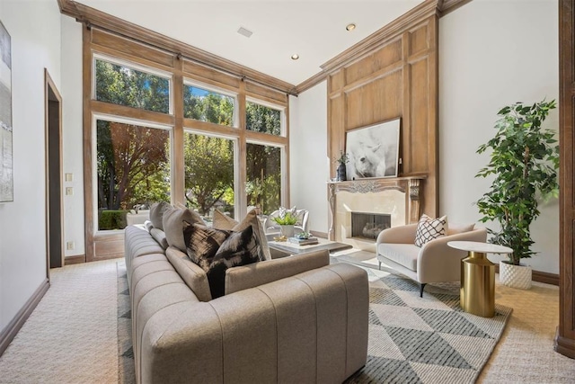 carpeted living room featuring crown molding, a high end fireplace, and a towering ceiling