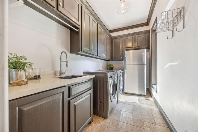 laundry room featuring sink, ornamental molding, cabinets, and washing machine and clothes dryer